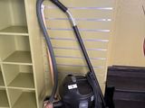 un aspirateur posé par terre à côté d'une bibliothèque