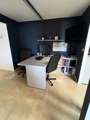 un bureau blanc avec une chaise noire dans un coin de la pièce