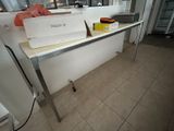 un ordinateur portable posé sur une table dans une cuisine où se trouve un réfrigérateur