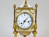 une horloge blanche et dorée sur laquelle est représenté un oiseau