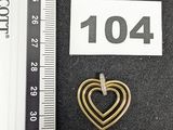 une photo d'une broche en forme de cœur doré avec une règle en arrière-plan