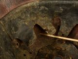a close up of a clock with a wooden stick sticking out of it