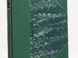 un vieux livre à la couverture verte posé sur une table blanche