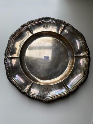 an antique silver plate on a white table next to a window
