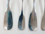 five spoons are lined up in a row on a white surface