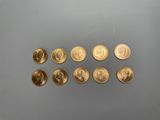 Plusieurs pièces d'or sont alignées sur une surface grise