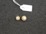 a pair of gold and pearl earrings on a black surface