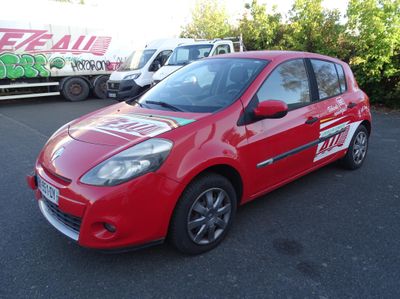 La voiture rouge est garée sur le parking, à côté du camion.