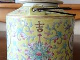 a yellow jar with flowers on it sitting on a table