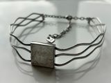 silver bracelet with a roman coin in the center and a chain around it
