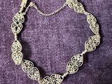 a close up of a silver bracelet on a purple background