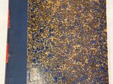 un livre bleu et doré posé sur une table blanche