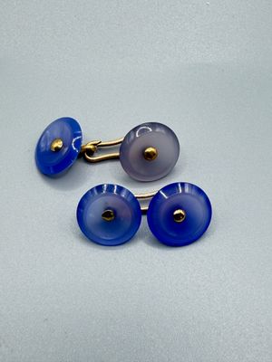 deux paires de boutons de manchette en verre bleu et blanc posés sur une surface blanche