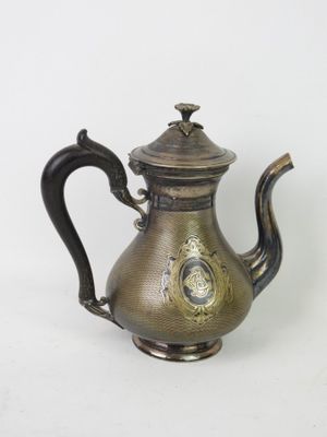 une théière ancienne en laiton, avec un couvercle et une anse, sur fond blanc