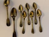 six spoons and a spoon rest on a white surface