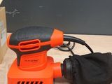 an orange electric sander sitting on top of a table next to a box