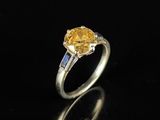 une bague sertie d'un saphir jaune et de diamants, posée sur un fond noir