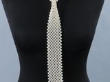 un gros plan sur un mannequin portant une cravate blanche ornée de perles