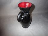 a black vase with a red handle on a table