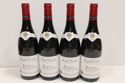 quatre bouteilles de vin rouge sont alignées sur une table