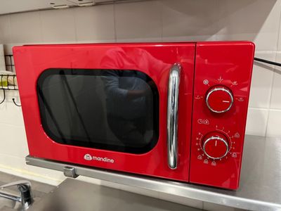 a red microwave oven sitting on a counter in a kitchen