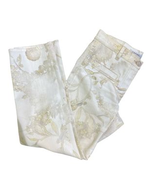 Le pantalon est blanc et doré, avec un motif floral.