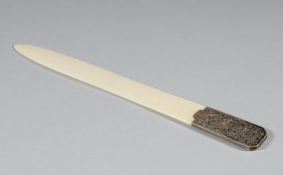 un couteau avec un manche posé sur une surface blanche