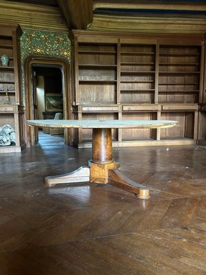 une table au milieu d'une pièce, avec des bibliothèques en arrière-plan