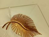 une broche en feuille d'or posée sur une assiette en verre transparent
