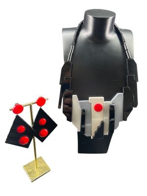 un mannequin noir avec des boutons rouges et un socle doré