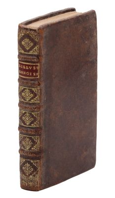 un vieux livre à la couverture brune posé sur une surface blanche