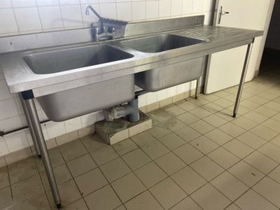 a stainless steel sink in the middle of a tiled floor