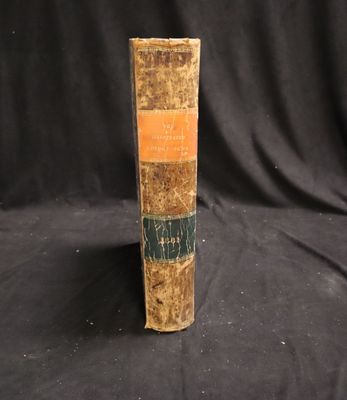 an old book sitting on top of a black cloth covered table