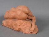 an image of a clay figurine of a sleeping woman on a rock