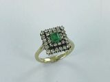 a close up of a ring with a green stone surrounded by white diamonds