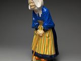 figurine of a woman in a blue dress and yellow skirt holding a cane