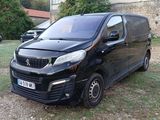 a small black van parked on the grass in front of a building