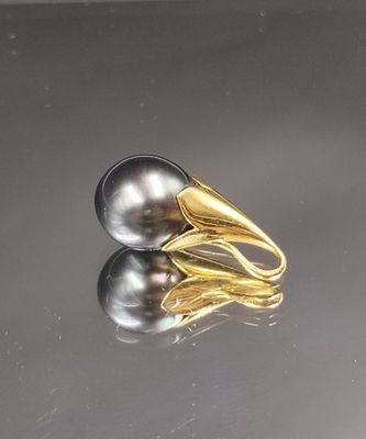 une bague en or sertie d'une perle noire, posée sur une table