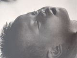 a black and white photo of a young boy laying on the ground