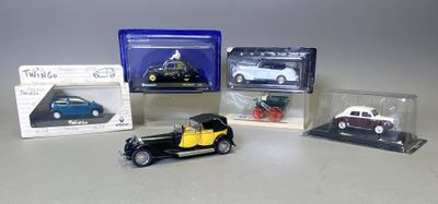 Quatre modèles réduits de voitures sont posés dans des boîtes en plastique sur une table.