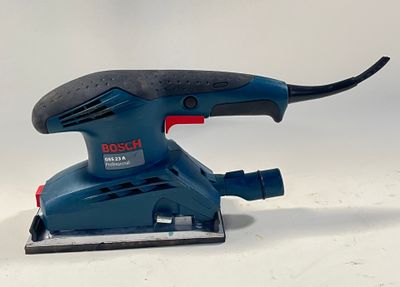 une ponceuse électrique bleue posée sur une surface blanche