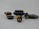 several pieces of blue and gold vases and bowls on a white surface