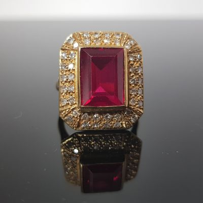 a close up of a ruby and diamond ring on a black surface