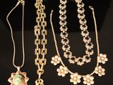 three necklaces and a pendant are displayed on a black surface