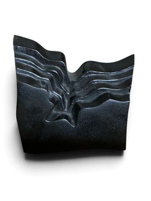une sculpture noire représentant un visage sur une surface blanche