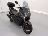 un scooter noir garé dans une pièce aux murs blancs