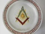 une assiette ornée d'un symbole maçonnique, posée sur une table