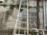 une échelle appuyée contre un mur, à côté d'une borne d'incendie