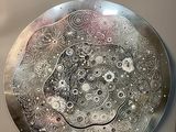 une plaque métallique ornée d'un motif, à côté d'une bouteille de vin