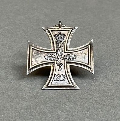 une vieille croix en argent surmontée d'une couronne, posée sur une table